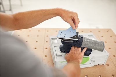 A tradesperson fits an abrasive to a sander
