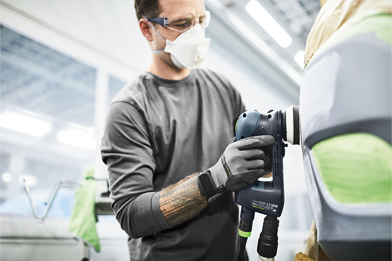 A man works on a surface with a Rotex sander