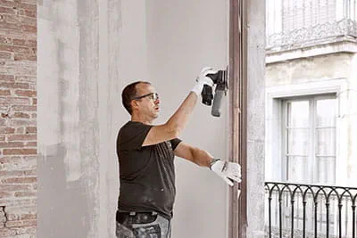A painter sands the window frames with the Festool cordless sander